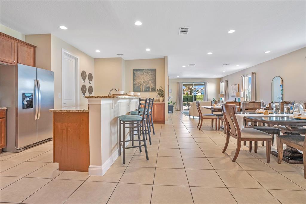 An open-concept kitchen and dining area features tile flooring, granite countertops, and stainless appliances — 631 LASSO DRIVE, KISSIMMEE, FL