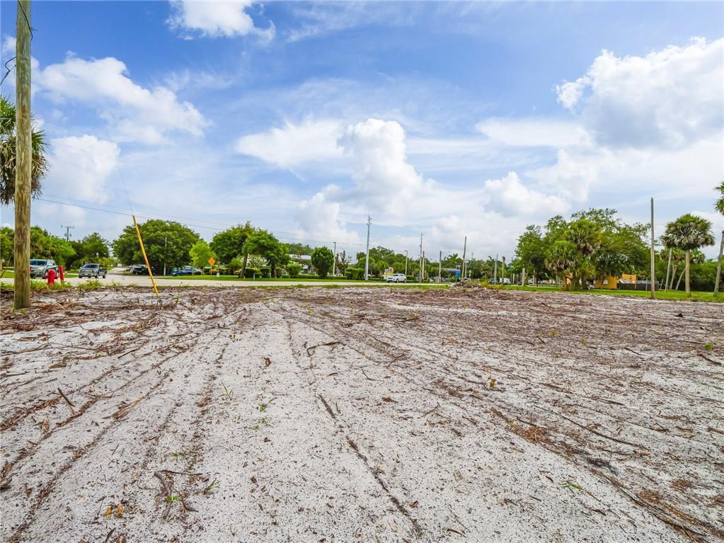A flat, cleared sandy lot with scattered debris and trees in the background — 445 Old Dixie Highway, Vero Beach FL 32962, VERO BEACH, FL