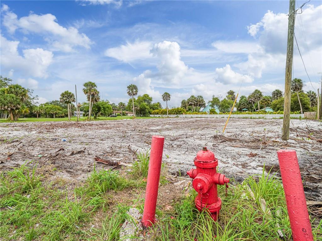A vacant, cleared lot features a red fire hydrant and two red bollards in the foreground — 445 Old Dixie Highway, Vero Beach FL 32962, VERO BEACH, FL