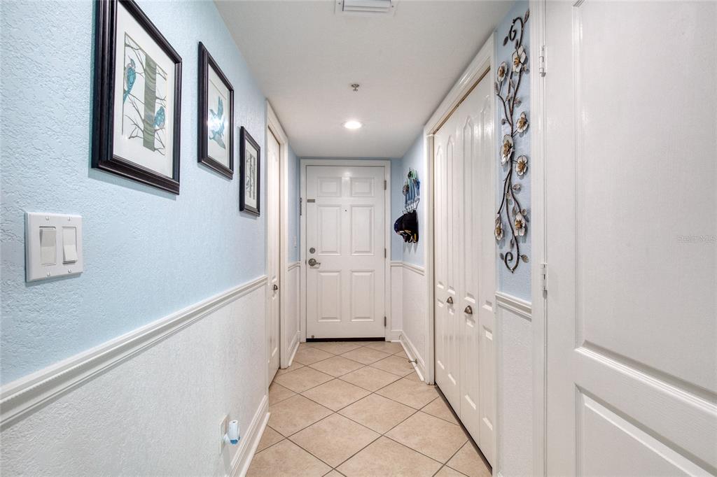 A hallway features light blue walls, white wainscoting, tile flooring, and a white entry door — 2937 S ATLANTIC AVENUE UNIT 1504, DAYTONA BEACH, FL