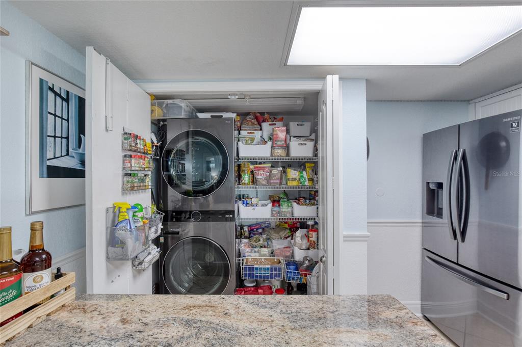 A kitchen features a stacked washer and dryer unit next to a pantry and refrigerator — 2937 S ATLANTIC AVENUE UNIT 1504, DAYTONA BEACH, FL