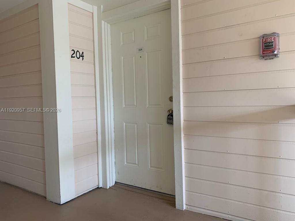 A white apartment door labeled 204 is set in a light-colored exterior wall — 907 NE 199th St # 204, Miami FL 33179, MIAMI, FL