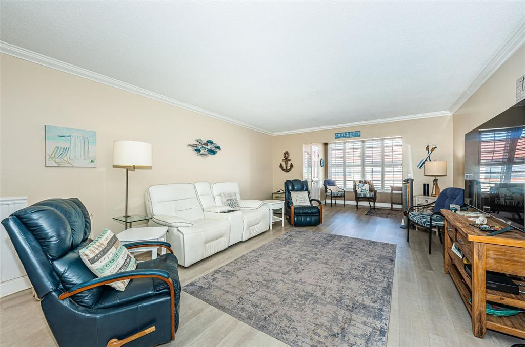 A living room features light wood flooring, a white sofa, and several blue leather recliners — 3010 59TH STREET S UNIT 302, GULFPORT, FL
