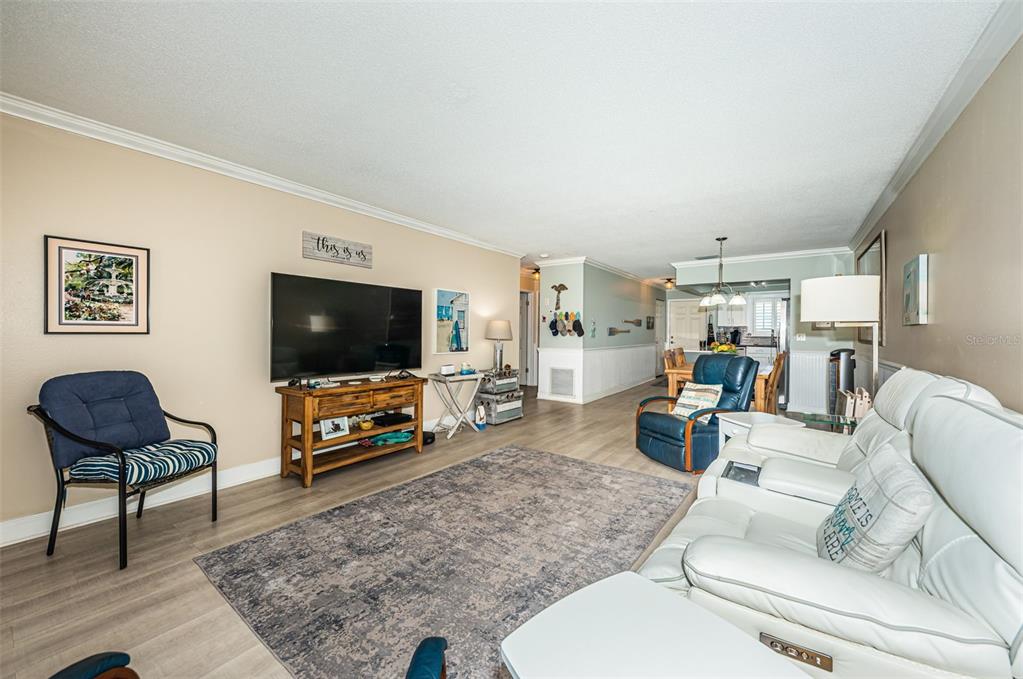 A living room features light wood-look flooring, a large television, and a white leather sofa — 3010 59TH STREET S UNIT 302, GULFPORT, FL