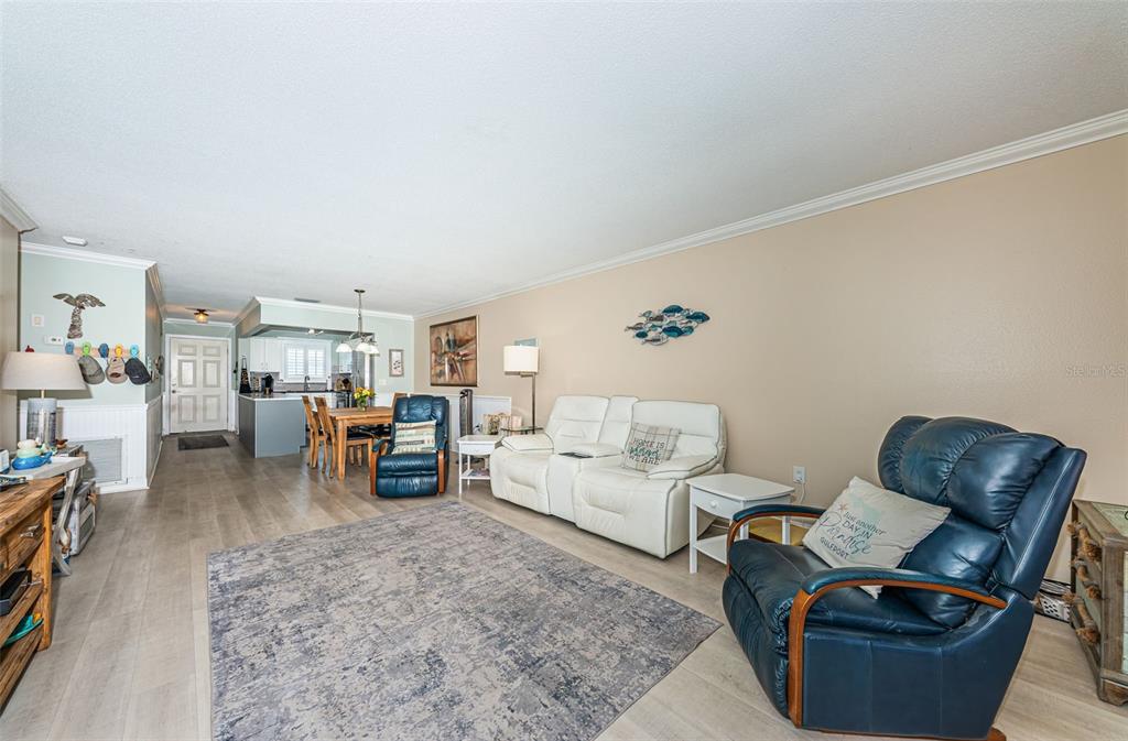 A living room features light wood-look flooring, a white sofa, and two blue leather recliners — 3010 59TH STREET S UNIT 302, GULFPORT, FL