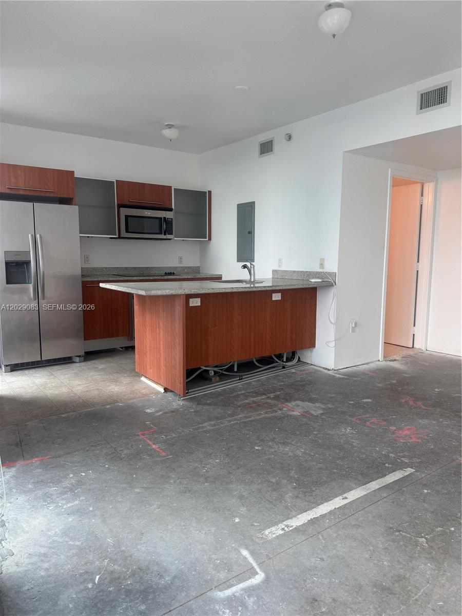 A kitchen with wood cabinets, stainless steel appliances, and a granite island on concrete flooring — 185 SW 7th St # 3900, Miami FL 33130, MIAMI, FL