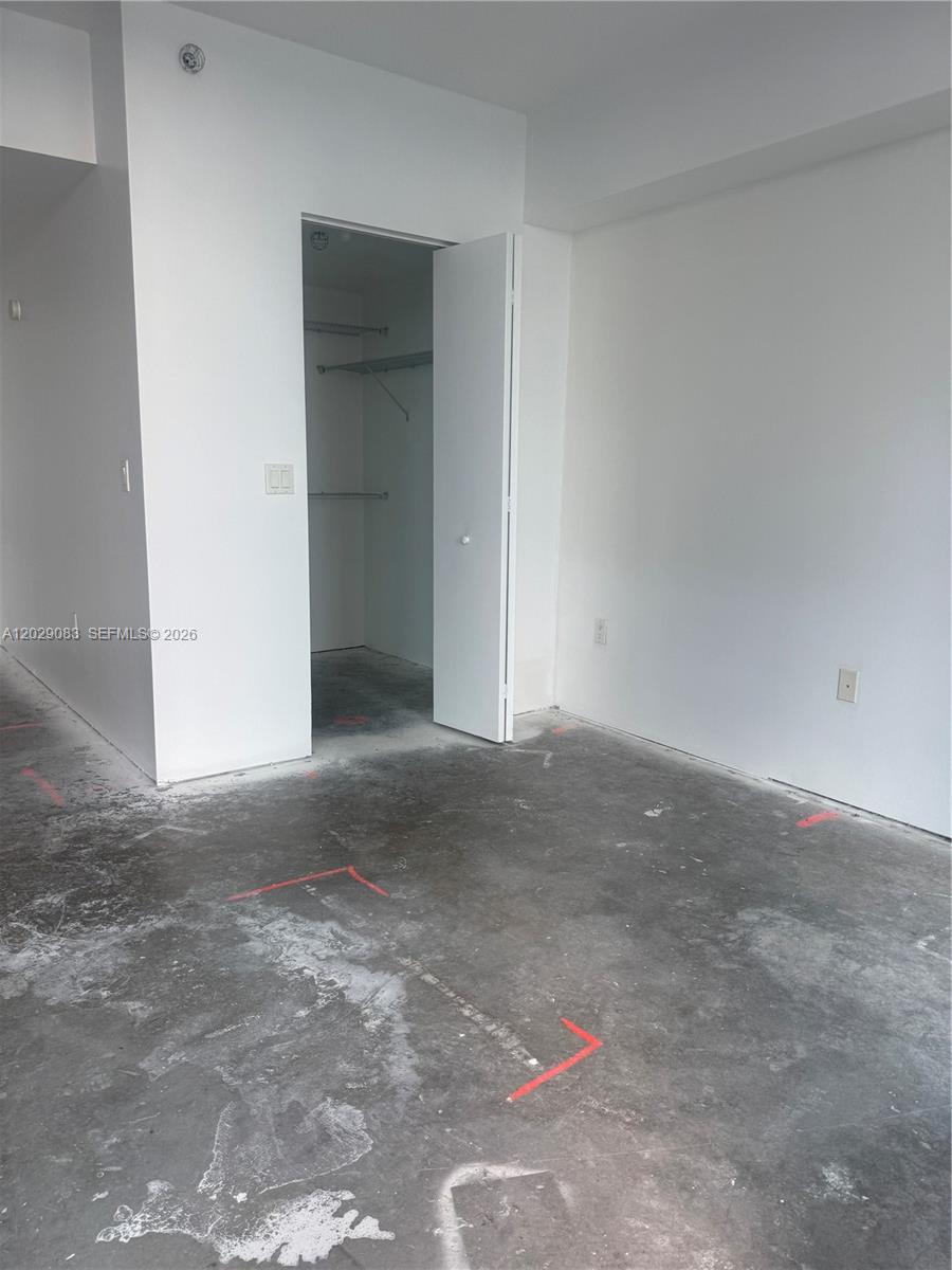 An unfinished room features bare concrete floors with red markings and an open closet — 185 SW 7th St # 3900, Miami FL 33130, MIAMI, FL