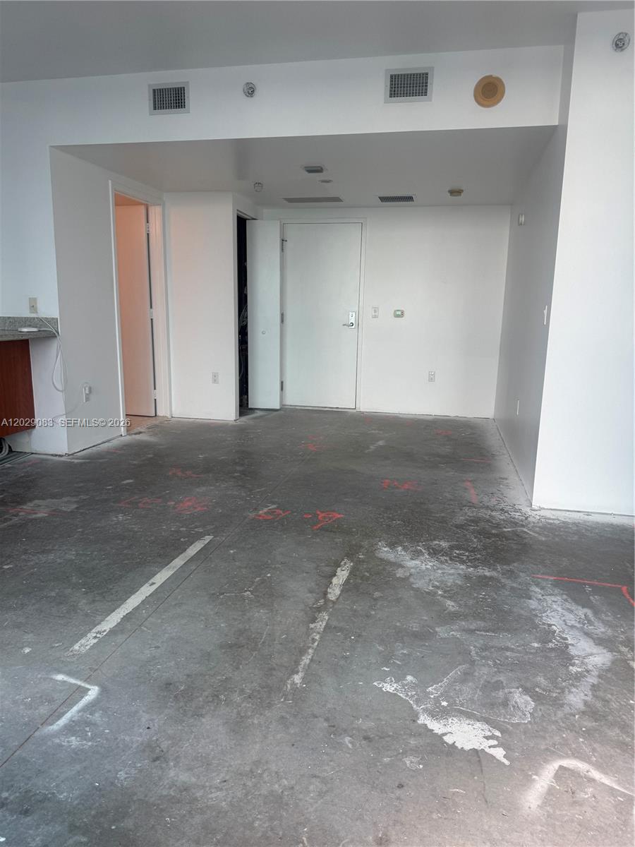 An unfinished room features exposed concrete flooring with red markings and white walls — 185 SW 7th St # 3900, Miami FL 33130, MIAMI, FL