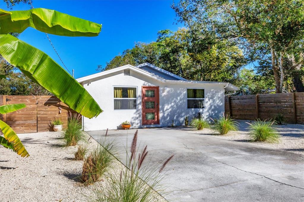 A single-story house with a concrete driveway and gravel yard enclosed by a wooden fence — 2441 NOVUS STREET, SARASOTA, FL
