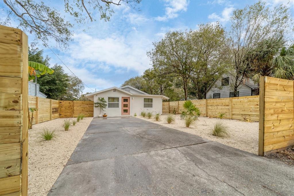 A kitchen features white cabinets, quartz countertops, floating shelves, and a tiled backsplash — 2441 NOVUS STREET, SARASOTA, FL