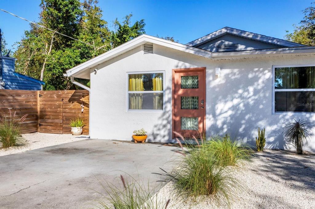 A white stucco house features a terracotta-colored front door and a concrete driveway — 2441 NOVUS STREET, SARASOTA, FL