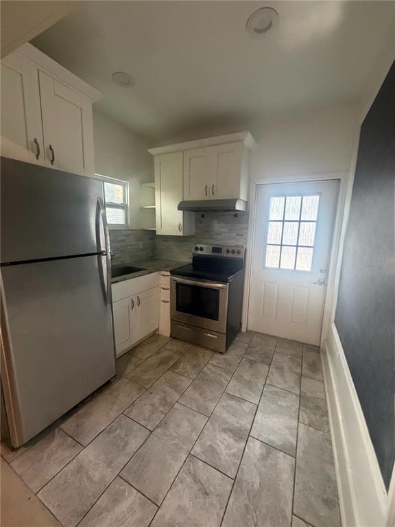 A kitchen features stainless steel appliances, white cabinetry, a tiled backsplash, and gray floor tiles — 819 6TH STREET N UNIT 2, ST PETERSBURG, FL
