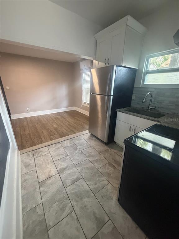 A kitchen with stainless steel appliances and tile flooring opens into a wood-floored living area — 819 6TH STREET N UNIT 2, ST PETERSBURG, FL