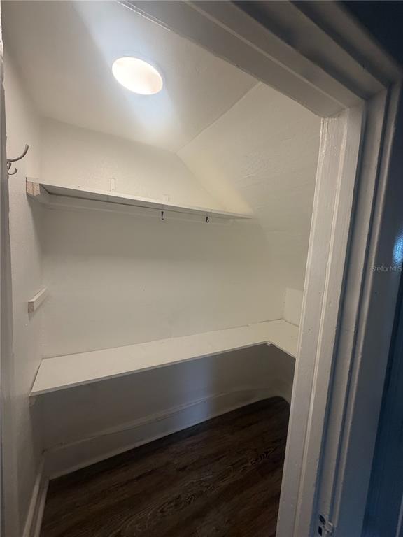 A small walk-in closet with white walls, two wooden shelves, and dark wood-look flooring — 819 6TH STREET N UNIT 2, ST PETERSBURG, FL