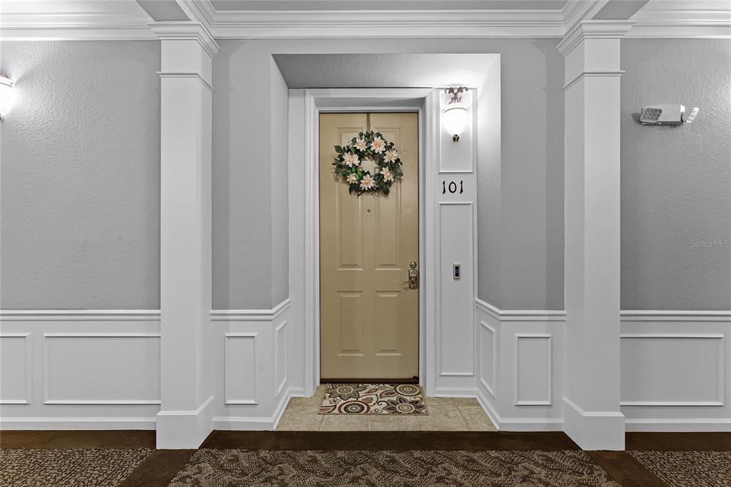 A beige front door with a floral wreath is framed by white columns and wainscoting — 3356 ROBERT TRENT JONES DRIVE UNIT 101, ORLANDO, FL