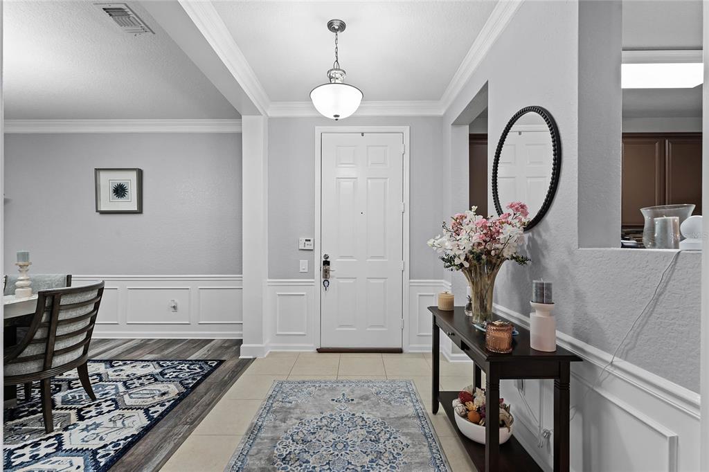 A bright entryway features tile flooring, a white front door, and a dark wood console table — 3356 ROBERT TRENT JONES DRIVE UNIT 101, ORLANDO, FL