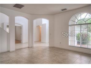 A bright room with light tile flooring, arched doorways, and a large arched window — 18178 SANDY POINTE DRIVE, TAMPA, FL