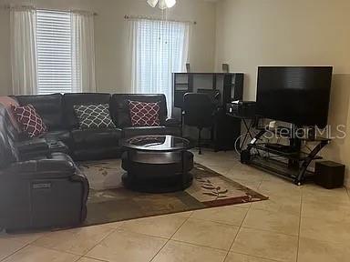A living room features a dark leather sectional, a glass coffee table, and a television — 4309 SUMMER BREEZE WAY, KISSIMMEE, FL