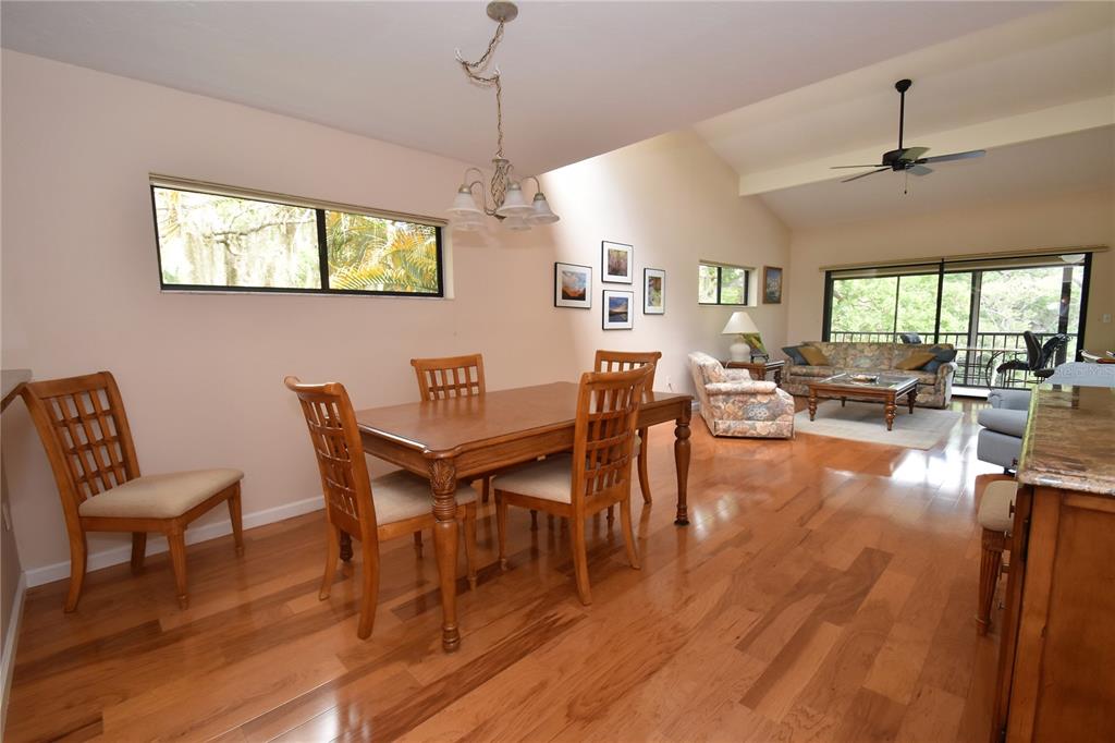 A dining area with a wooden table and chairs flows into a living room with hardwood floors — 1523 CLOWER CREEK DRIVE UNIT HA246, SARASOTA, FL