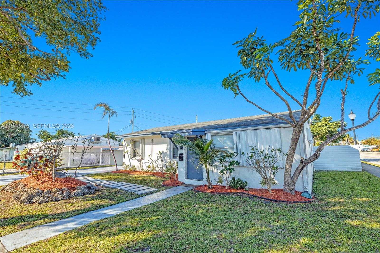A single-story white house with a gray door and a front yard with landscaping — 822 N 20th Ave, Hollywood FL 33020, HOLLYWOOD, FL