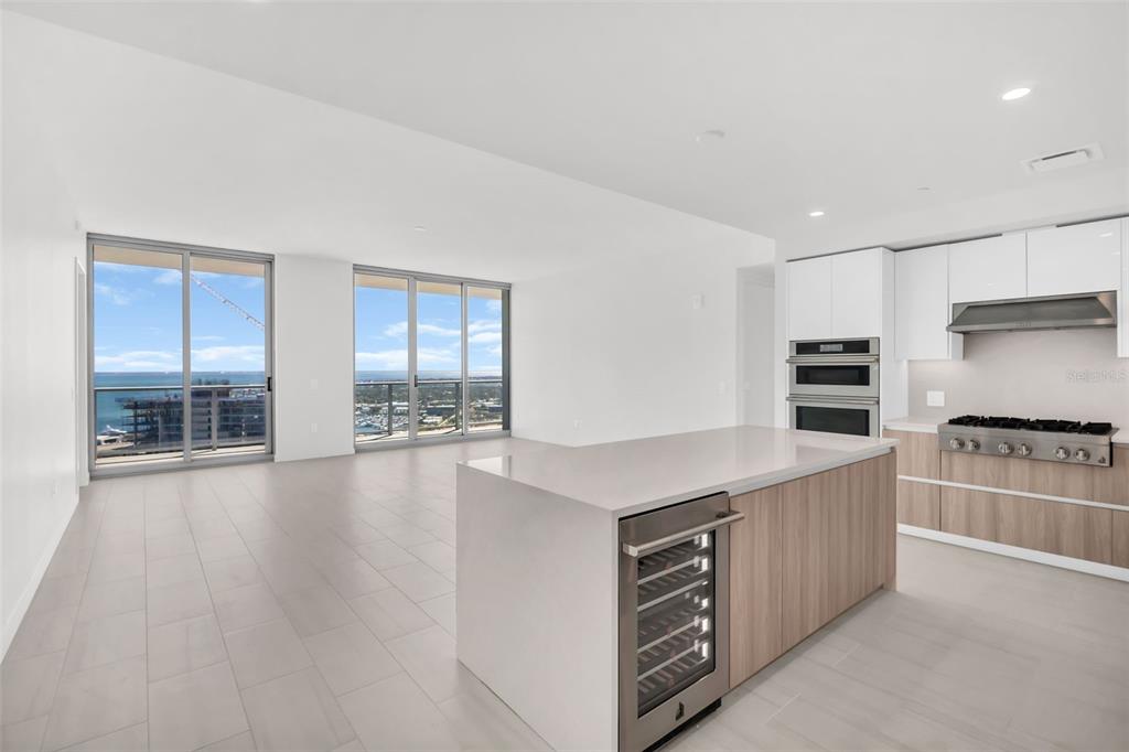 A modern kitchen with a center island and wine cooler overlooks a bright living area — 400 CENTRAL AVENUE UNIT 3606, ST PETERSBURG, FL