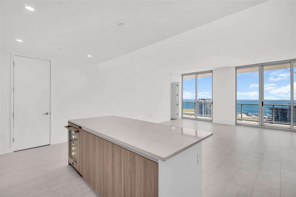 A modern kitchen island with a wine cooler sits in a bright, open-plan living space — 400 CENTRAL AVENUE UNIT 3606, ST PETERSBURG, FL