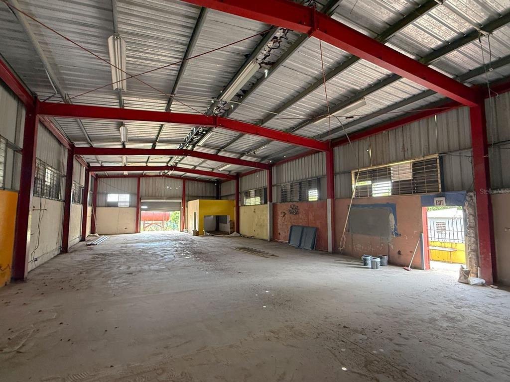 An empty industrial warehouse space features a concrete floor, exposed red steel beams, and windows — KM 1.6 ROUTE 200, VIEQUES, PR