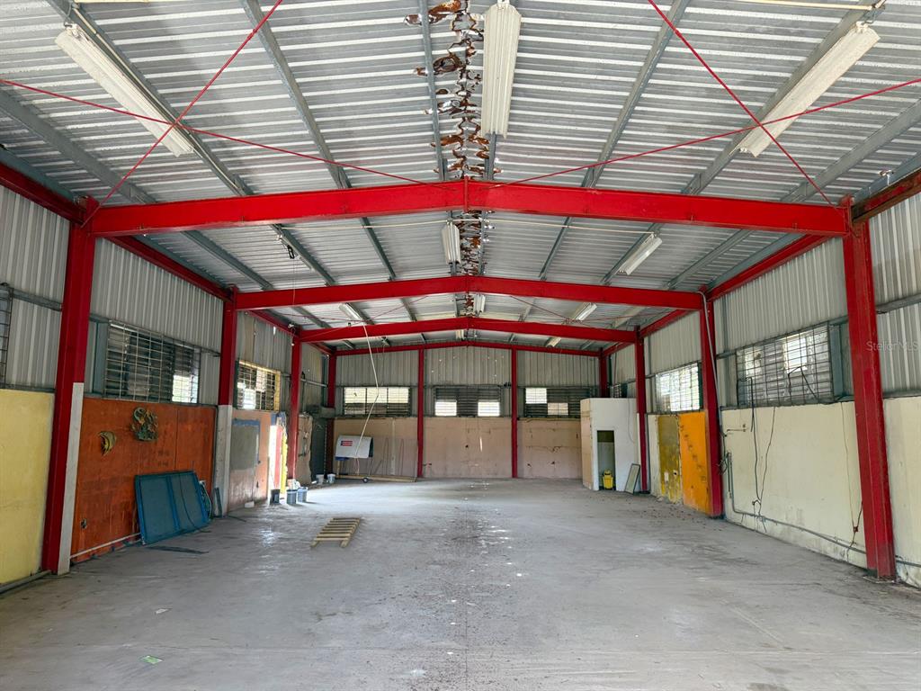 An empty industrial warehouse space features a high metal ceiling, red steel beams, and concrete floors — KM 1.6 ROUTE 200, VIEQUES, PR