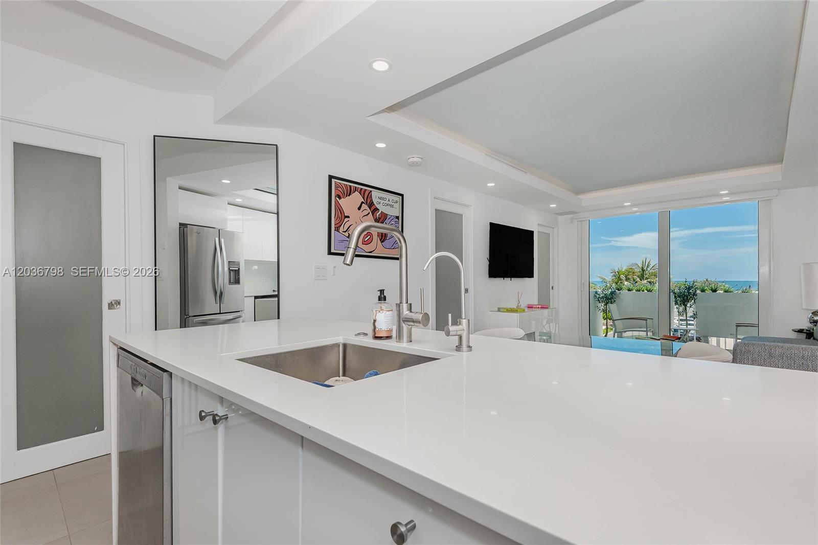 A modern white kitchen island with a stainless steel sink overlooks a bright living area — 345 Ocean Dr # 326, Miami Beach FL 33139, MIAMI BEACH, FL