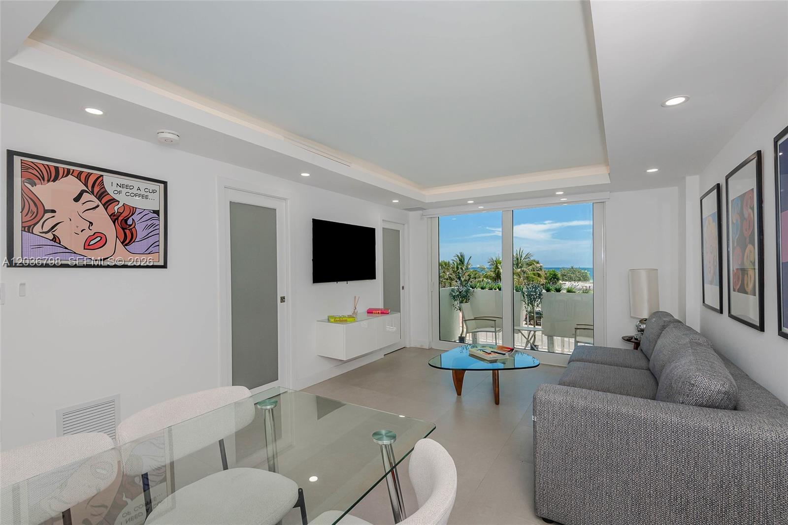 A modern living and dining area with a glass table, gray sofa, and balcony view — 345 Ocean Dr # 326, Miami Beach FL 33139, MIAMI BEACH, FL