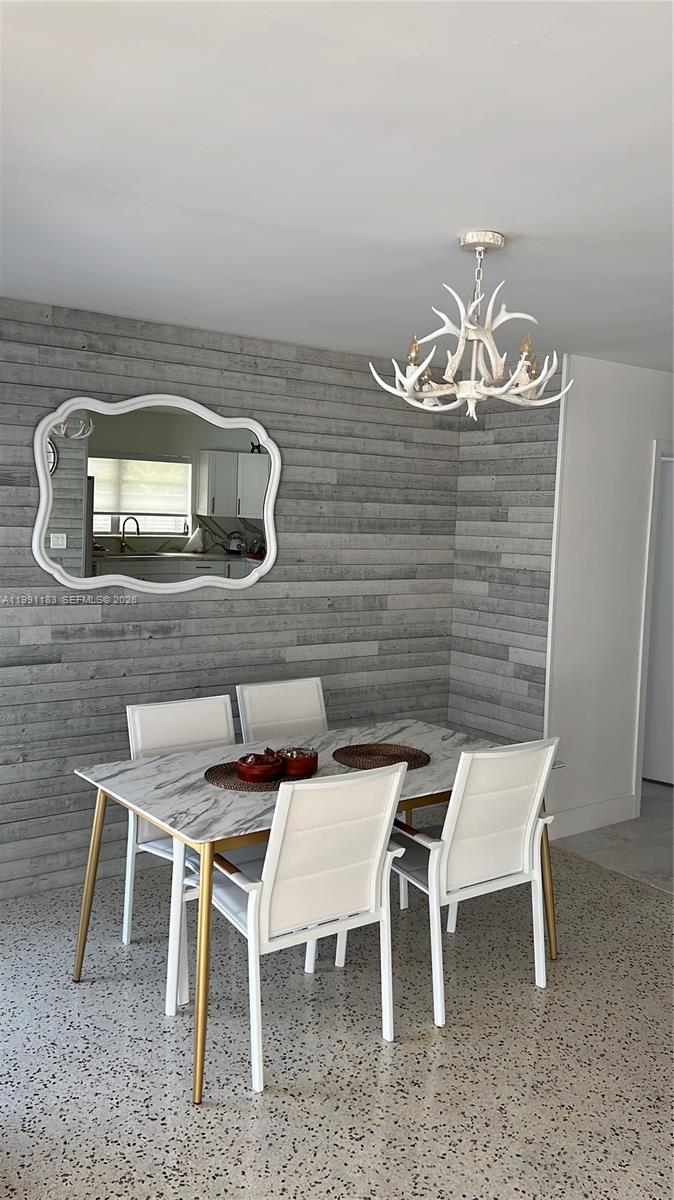 A dining room features a marble-topped table, white chairs, a mirror, and a chandelier — 750 Polk St, Hollywood FL 33019, HOLLYWOOD, FL