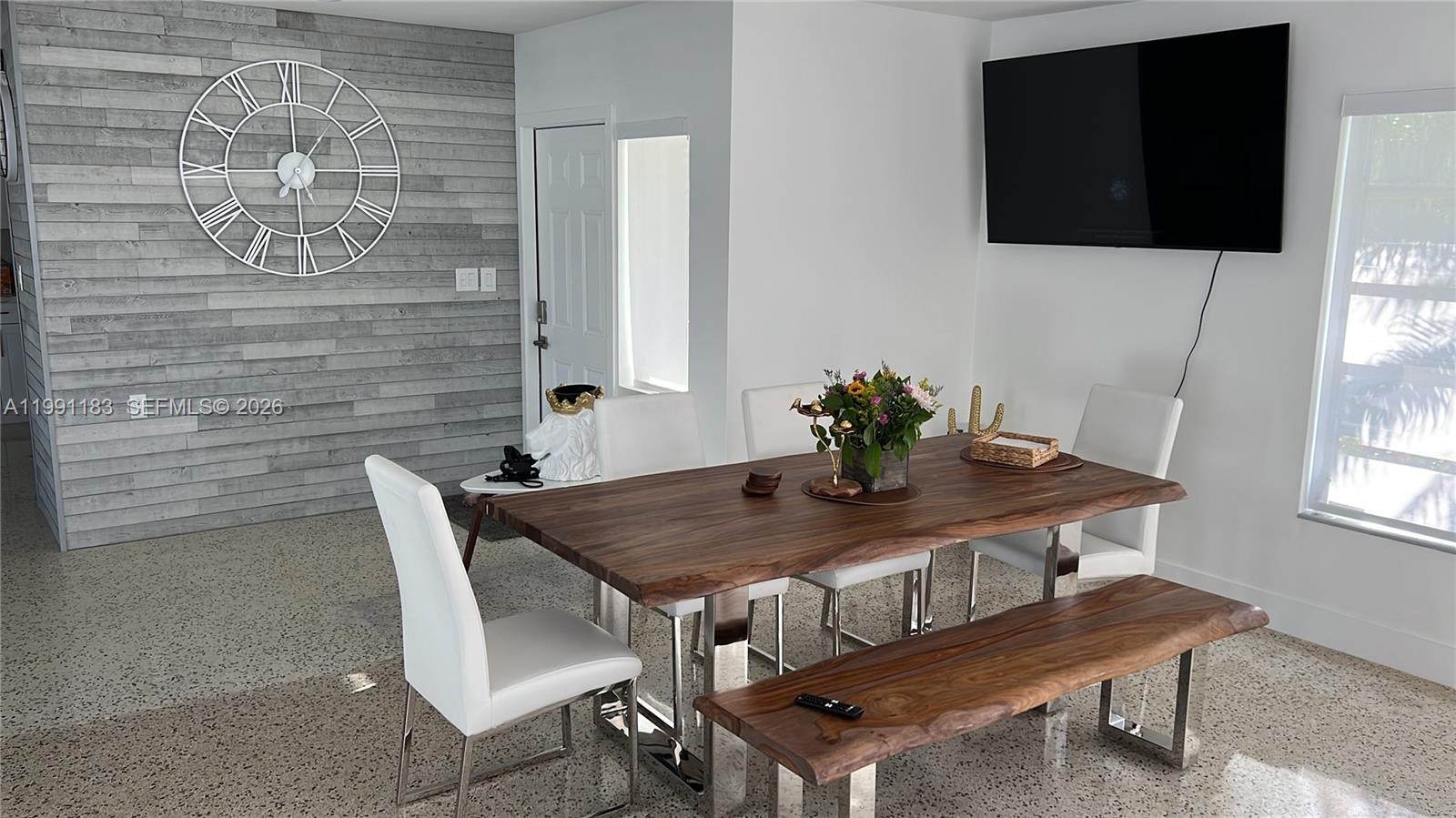 A dining room features a live-edge wood table, white chairs, a bench, and a clock — 750 Polk St, Hollywood FL 33019, HOLLYWOOD, FL