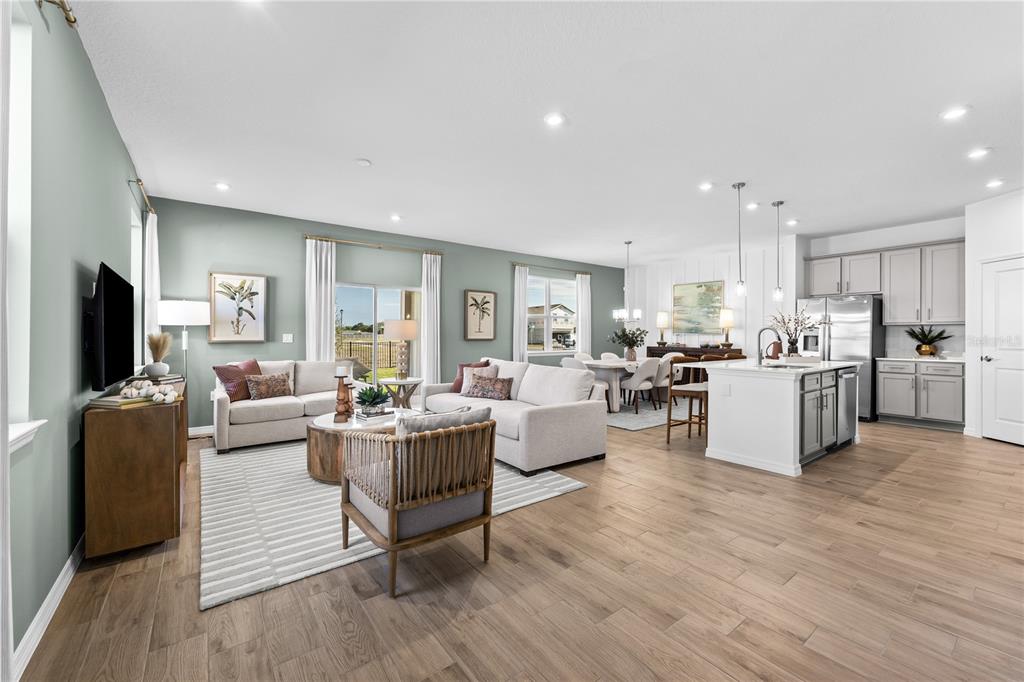 An open-concept living and dining area features light wood floors, gray walls, and white cabinetry — 1142 BANFF DRIVE NE, PALM BAY, FL