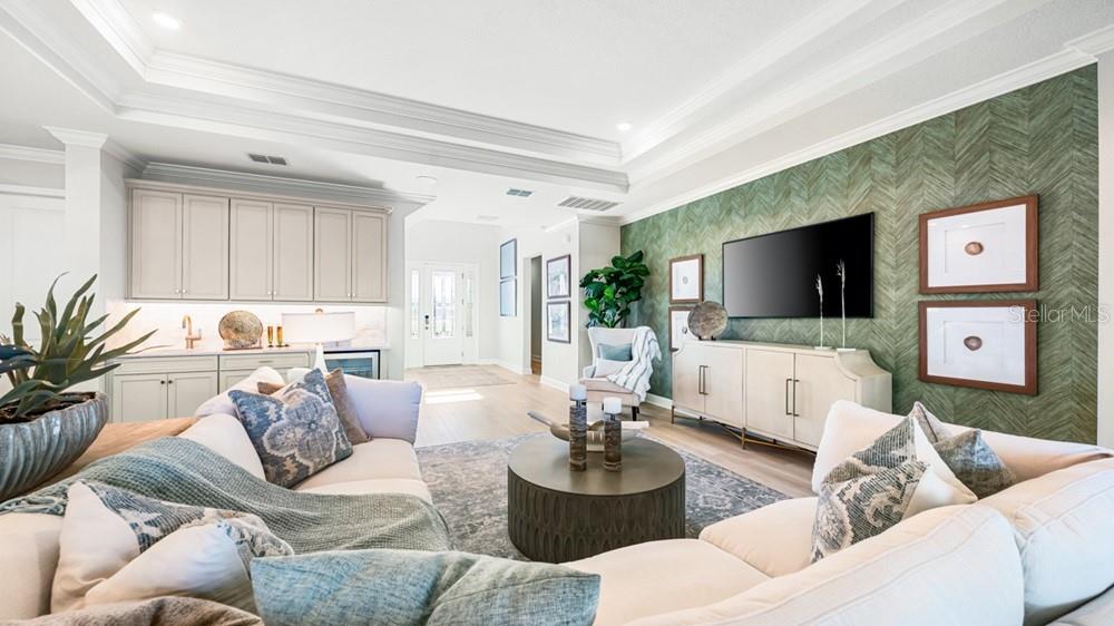 A living room features a green herringbone accent wall, a sectional sofa, and cabinetry — 16286 ALPHA GROVE PLACE, ODESSA, FL