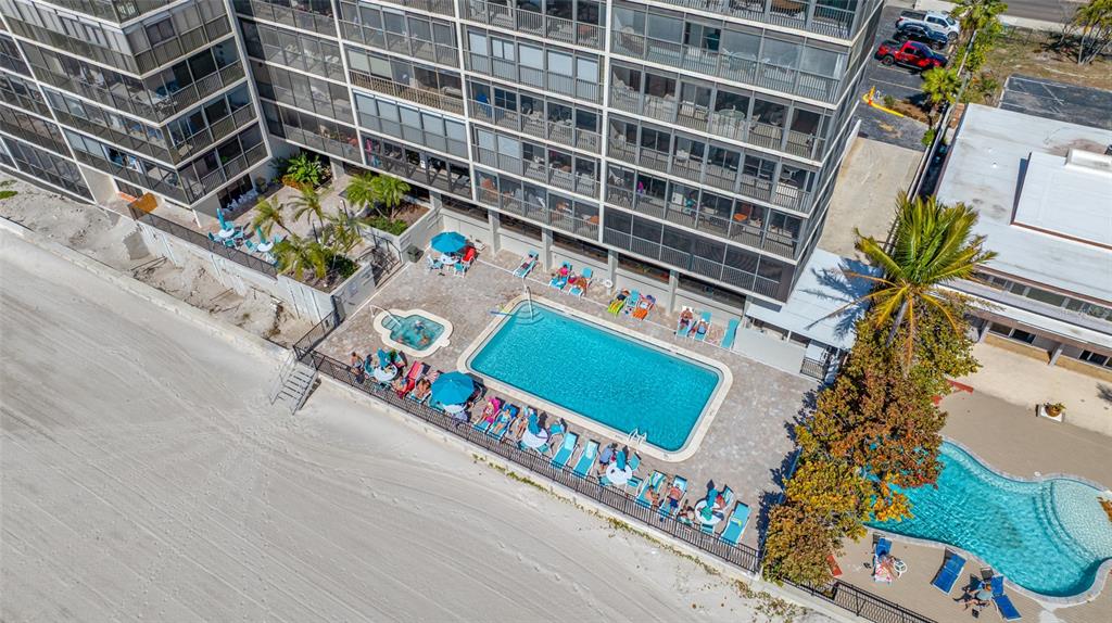 An aerial view shows a multi-story beachfront building with two swimming pools and lounge chairs — 15462 GULF BOULEVARD UNIT 603, MADEIRA BEACH, FL