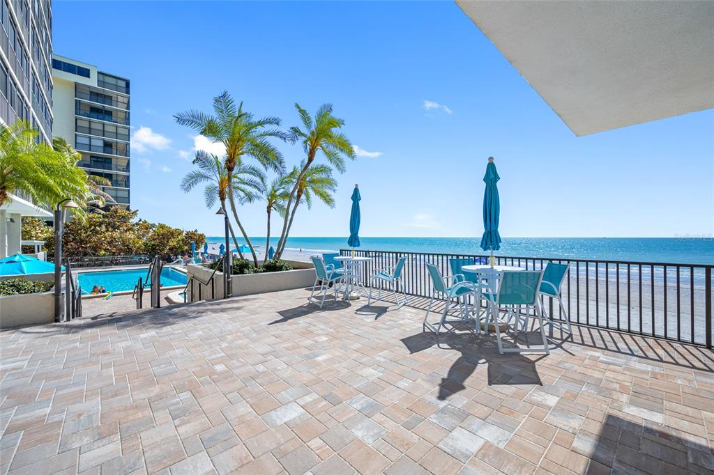 A paved patio overlooks a swimming pool, palm trees, and the ocean — 15462 GULF BOULEVARD UNIT 603, MADEIRA BEACH, FL