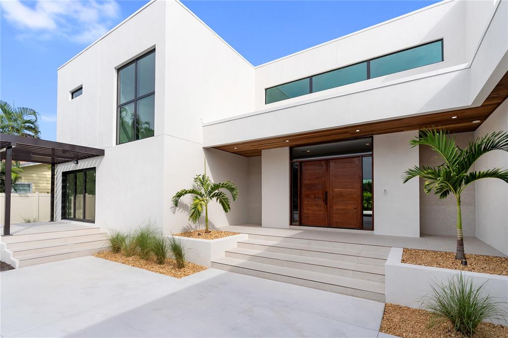 A modern white house exterior features a wooden double door entrance and concrete steps — 1759 WALDEMERE STREET, SARASOTA, FL