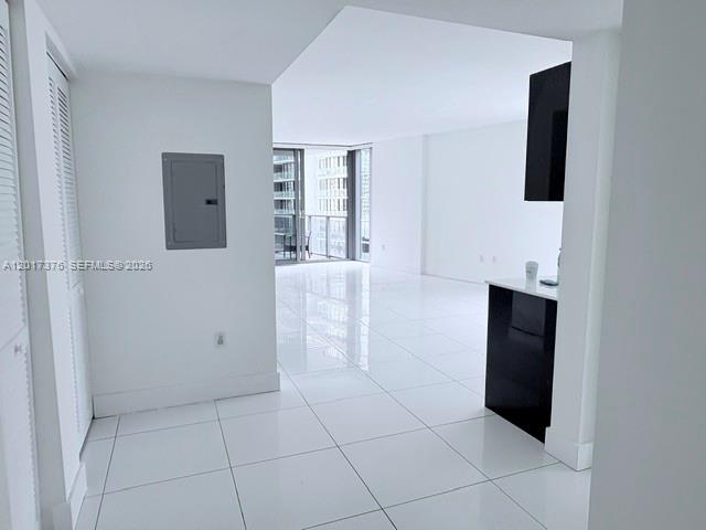 A bright, open-concept room features white tiled floors, a black kitchen island, and balcony access — 31 SE 6th St # 2001, Miami FL 33131, MIAMI, FL