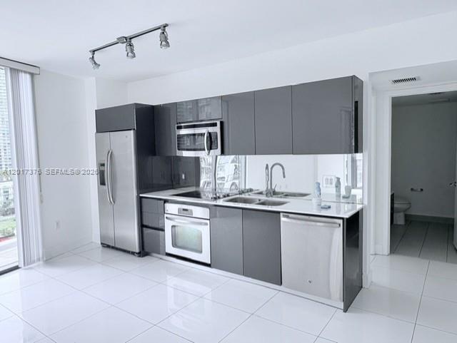 A modern kitchen features gray cabinets, stainless steel appliances, and white tile flooring — 31 SE 6th St # 2001, Miami FL 33131, MIAMI, FL