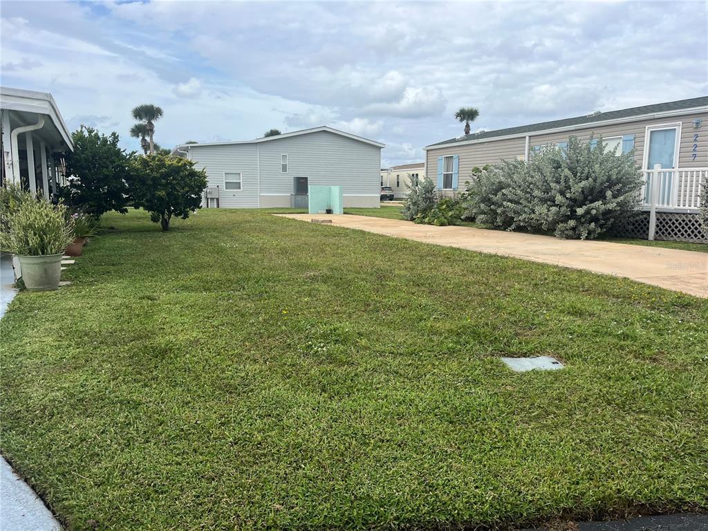 A grassy yard sits between two mobile homes with a concrete driveway on the right — 228 STARBOARD DRIVE, FLAGLER BEACH, FL