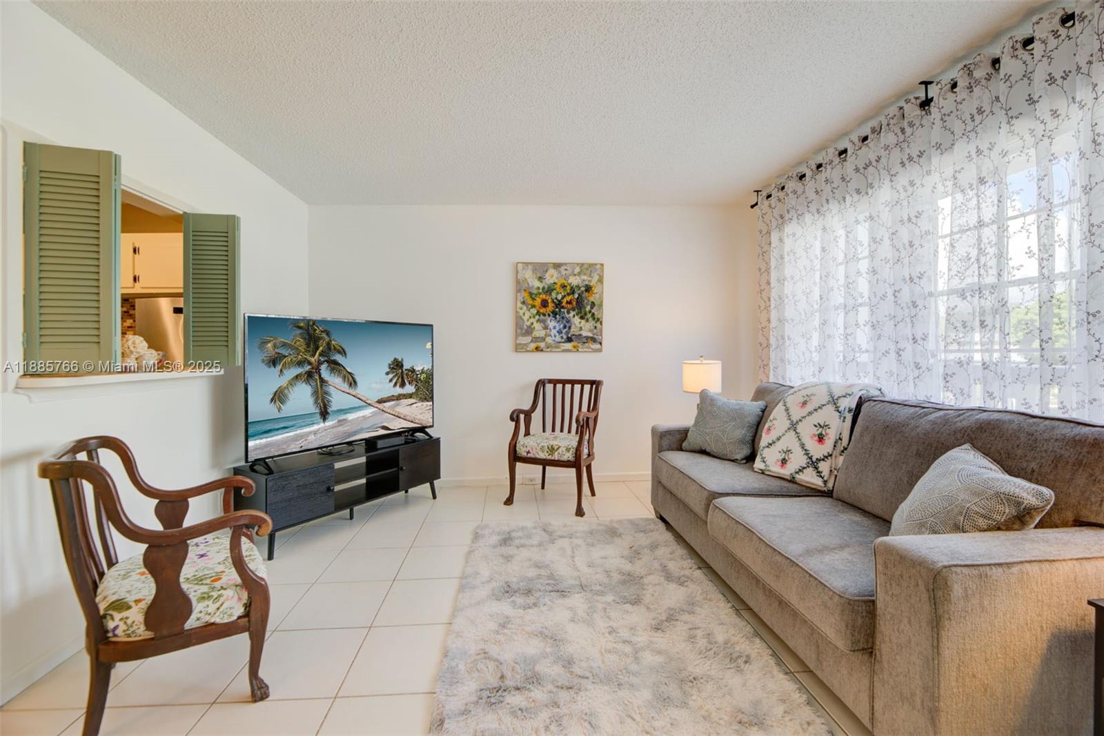 A living room features a gray sofa, two wooden chairs, a television, and tile flooring — 2031 Durham B # 2031, Deerfield Beach FL 33442, DEERFIELD BEACH, FL