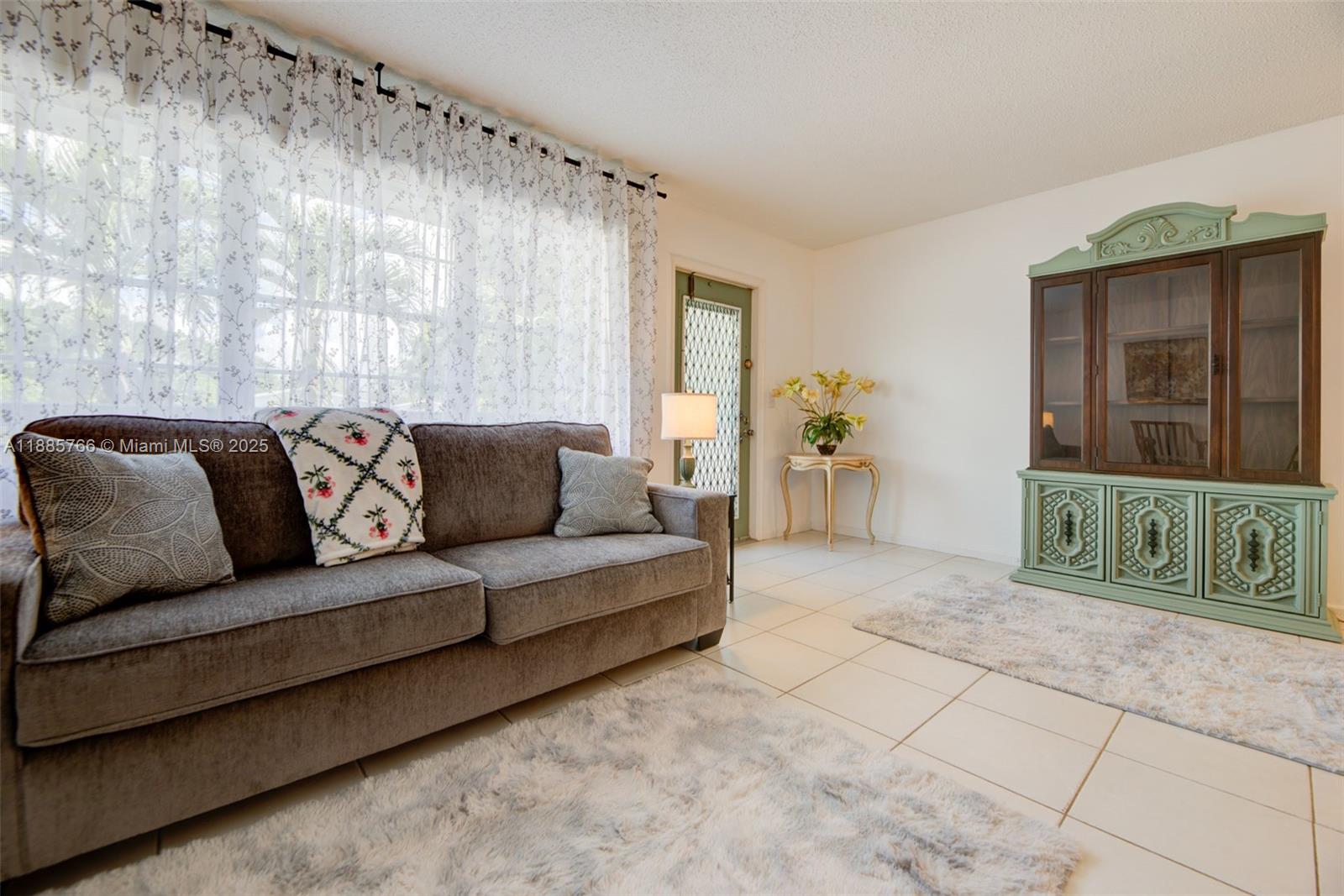 A living room features a gray sofa, a green hutch, and tile flooring — 2031 Durham B # 2031, Deerfield Beach FL 33442, DEERFIELD BEACH, FL