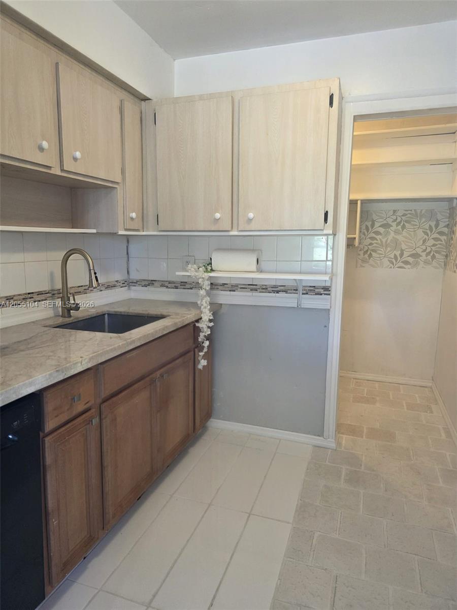 A kitchen features light wood upper cabinets, brown lower cabinets, and a tiled floor — 46 NW 14th Ct, Dania Beach FL 33004, DANIA BEACH, FL
