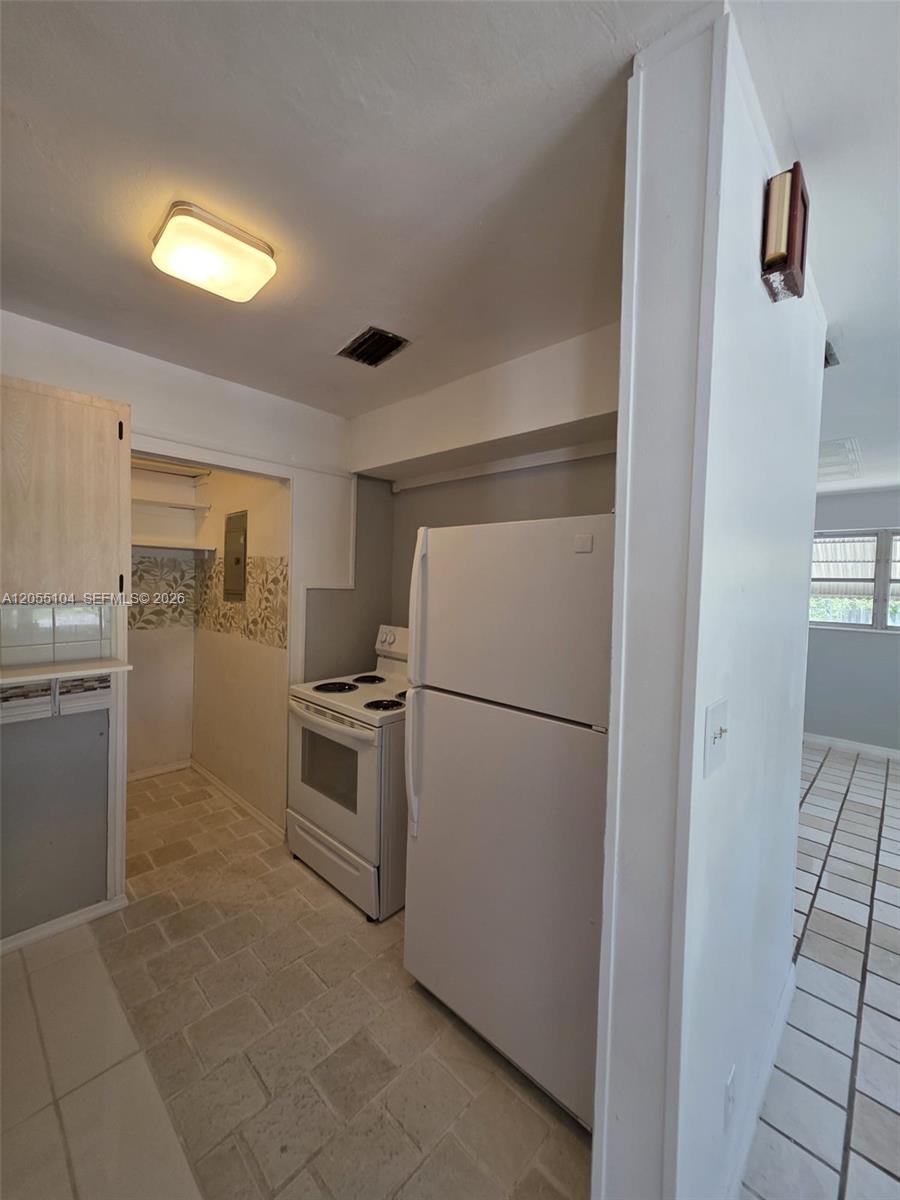 A kitchen features a white refrigerator, a white electric stove, and light-colored tile flooring — 46 NW 14th Ct, Dania Beach FL 33004, DANIA BEACH, FL