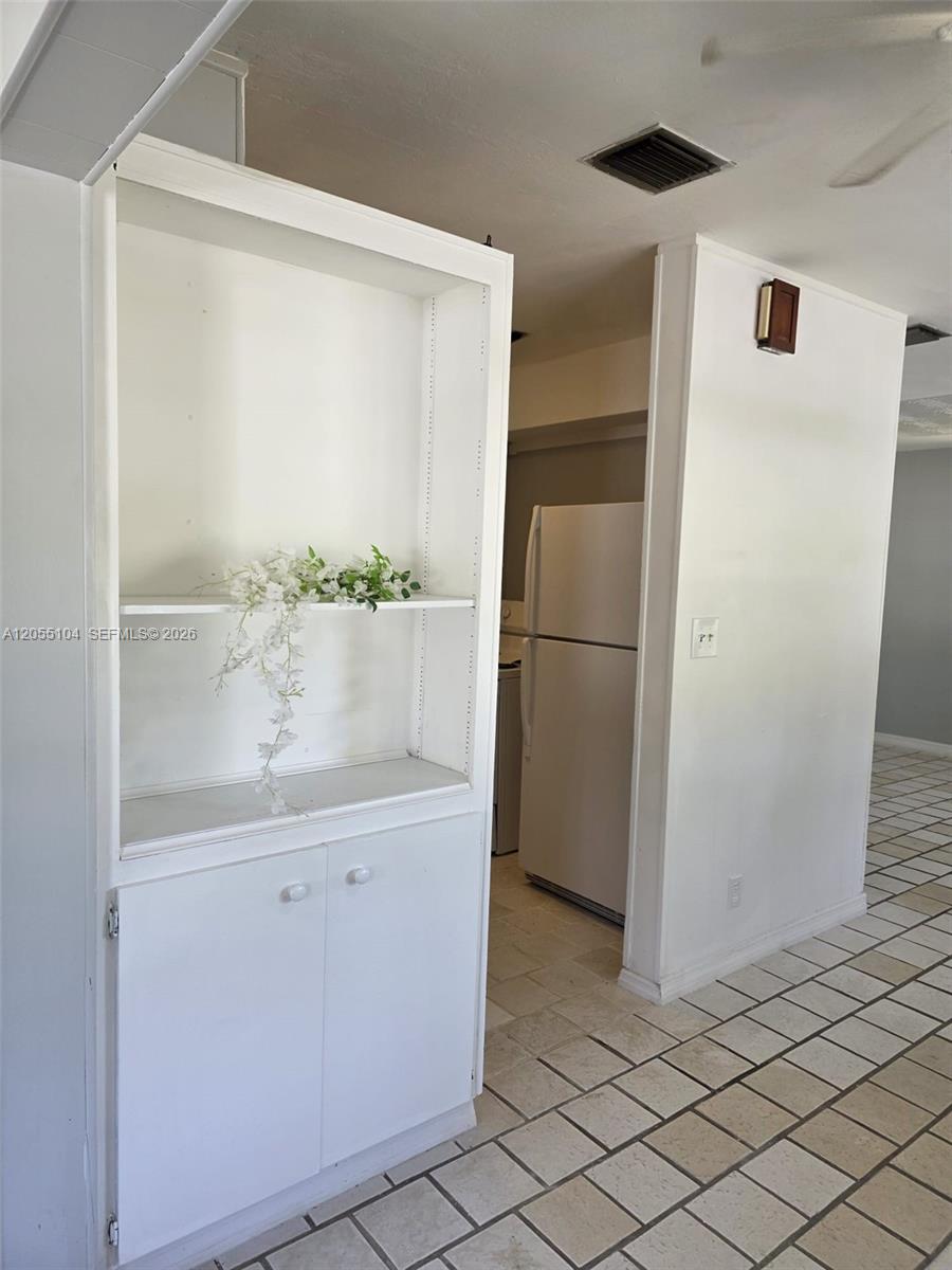 A white built-in shelving unit stands next to a kitchen with a white refrigerator — 46 NW 14th Ct, Dania Beach FL 33004, DANIA BEACH, FL