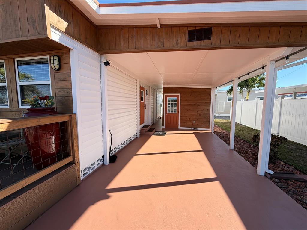 A covered carport area features a painted concrete floor, wood-paneled walls, and two exterior doors — 2216 PENNSYLVANIA AVENUE, BRADENTON, FL