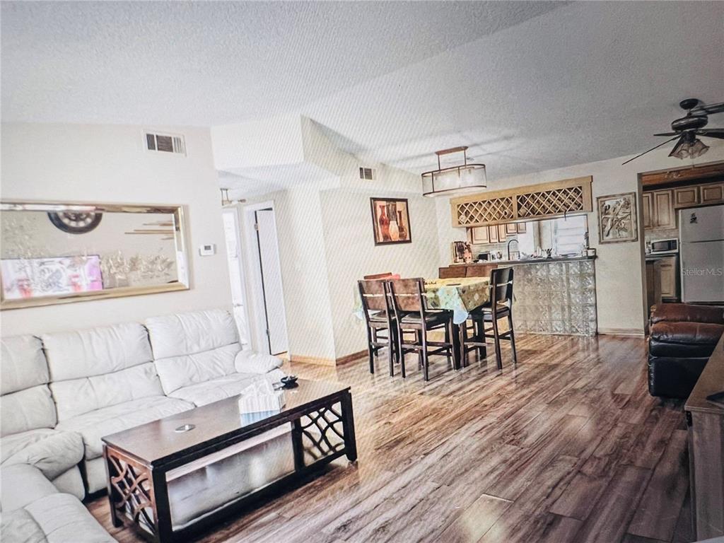 An open-concept living and dining area features wood-look flooring, a white sofa, and glass-block accents — 5543 MOOG ROAD, NEW PORT RICHEY, FL