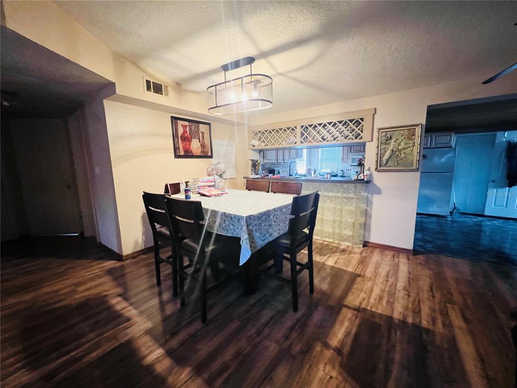 A dining area features a table with chairs, a pendant light, and a kitchen pass-through — 5543 MOOG ROAD, NEW PORT RICHEY, FL