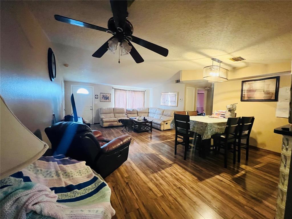 A living and dining room with wood-look flooring, a ceiling fan, and leather furniture — 5543 MOOG ROAD, NEW PORT RICHEY, FL