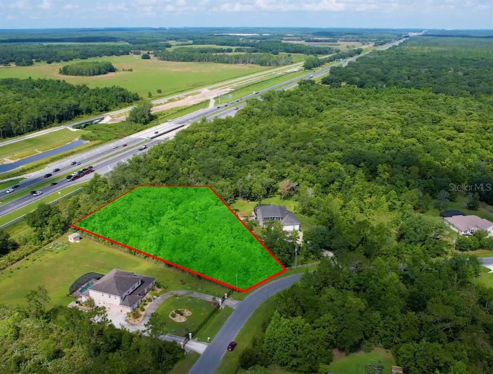 An aerial view shows a wooded lot outlined in red next to a highway — Lot 32 STARRY STREET, ORLANDO, FL
